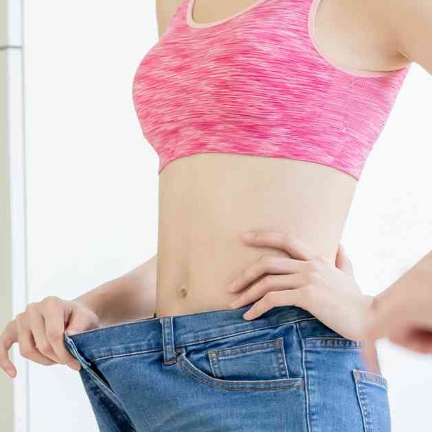woman looking in mirror wearing jeans too big
