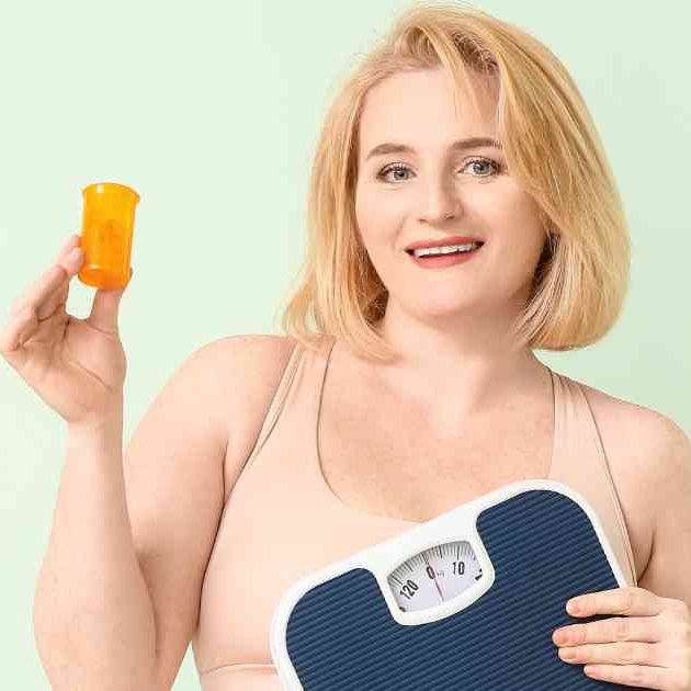 girl holding weight loss supplements and scales