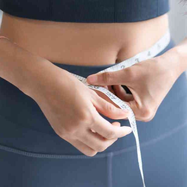 woman in workout gear measuring waist
