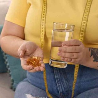 woman holding glass of water and weight loss supplements