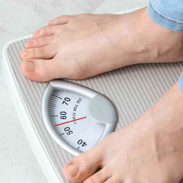 person in bare feet and jeans standing on scales