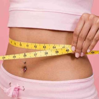 woman in pink workout gear measuring waist