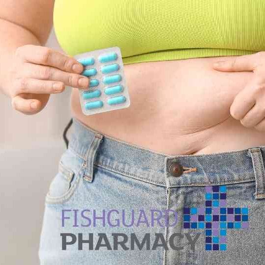 woman in green crop top holding weight loss pills